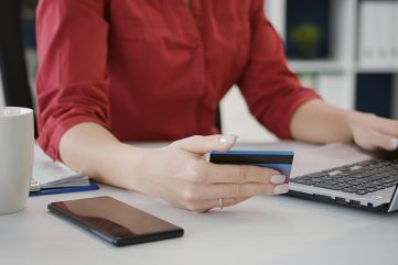 Femme gérant ses comptes sur une banque en ligne avec une carte bancaire et un ordinateur portable